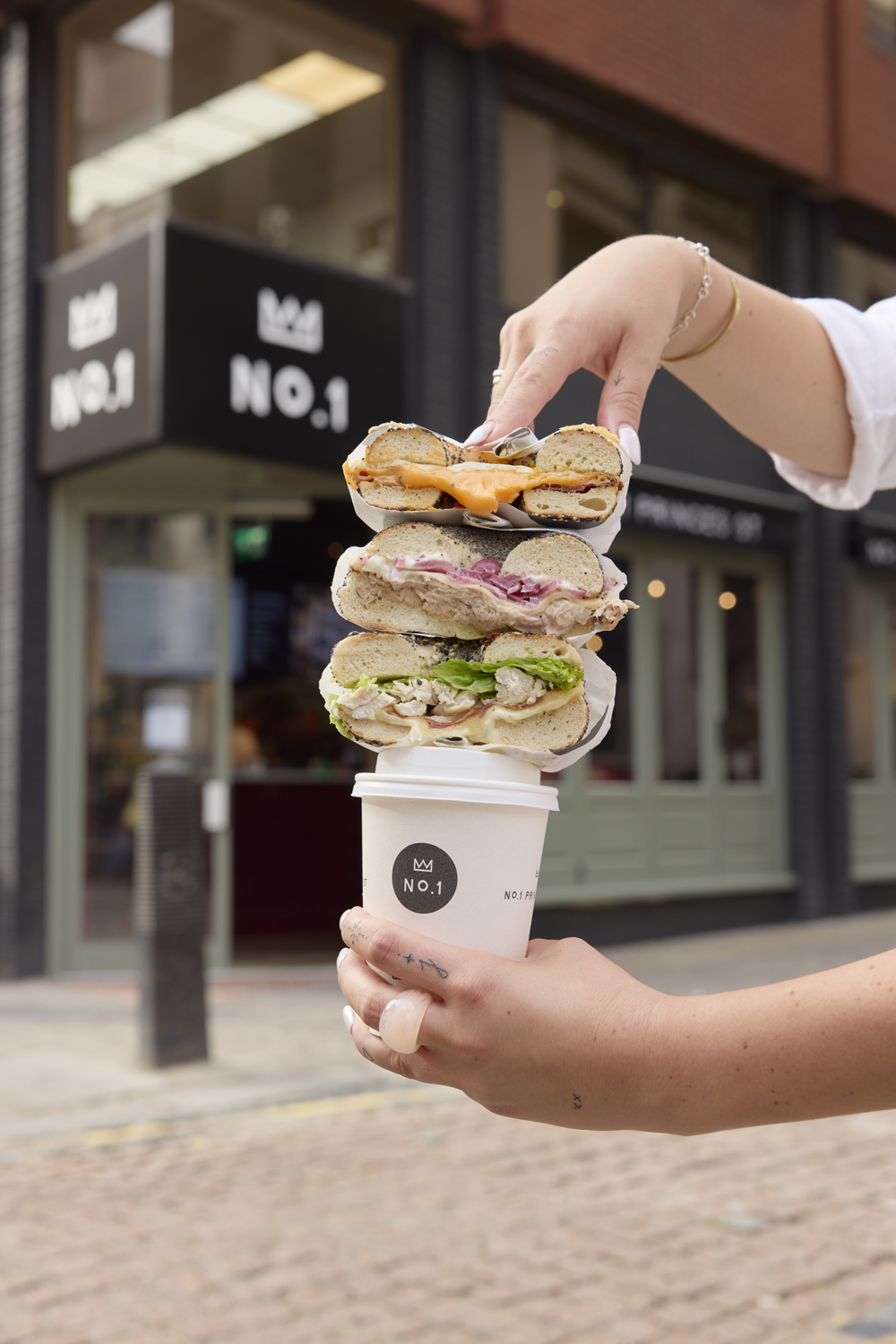 A stack of bagel sandwiches balanced on a No.1 cup outside the shop